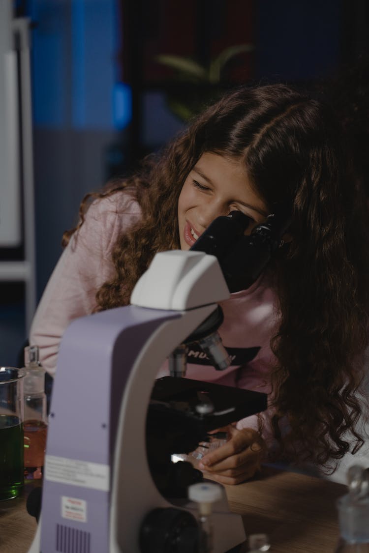 A Young Girl Looking Through A Microscope