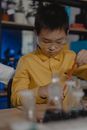 一名穿着黄色衬衫的亚洲孩子正在教室里用有色液体做化学实验