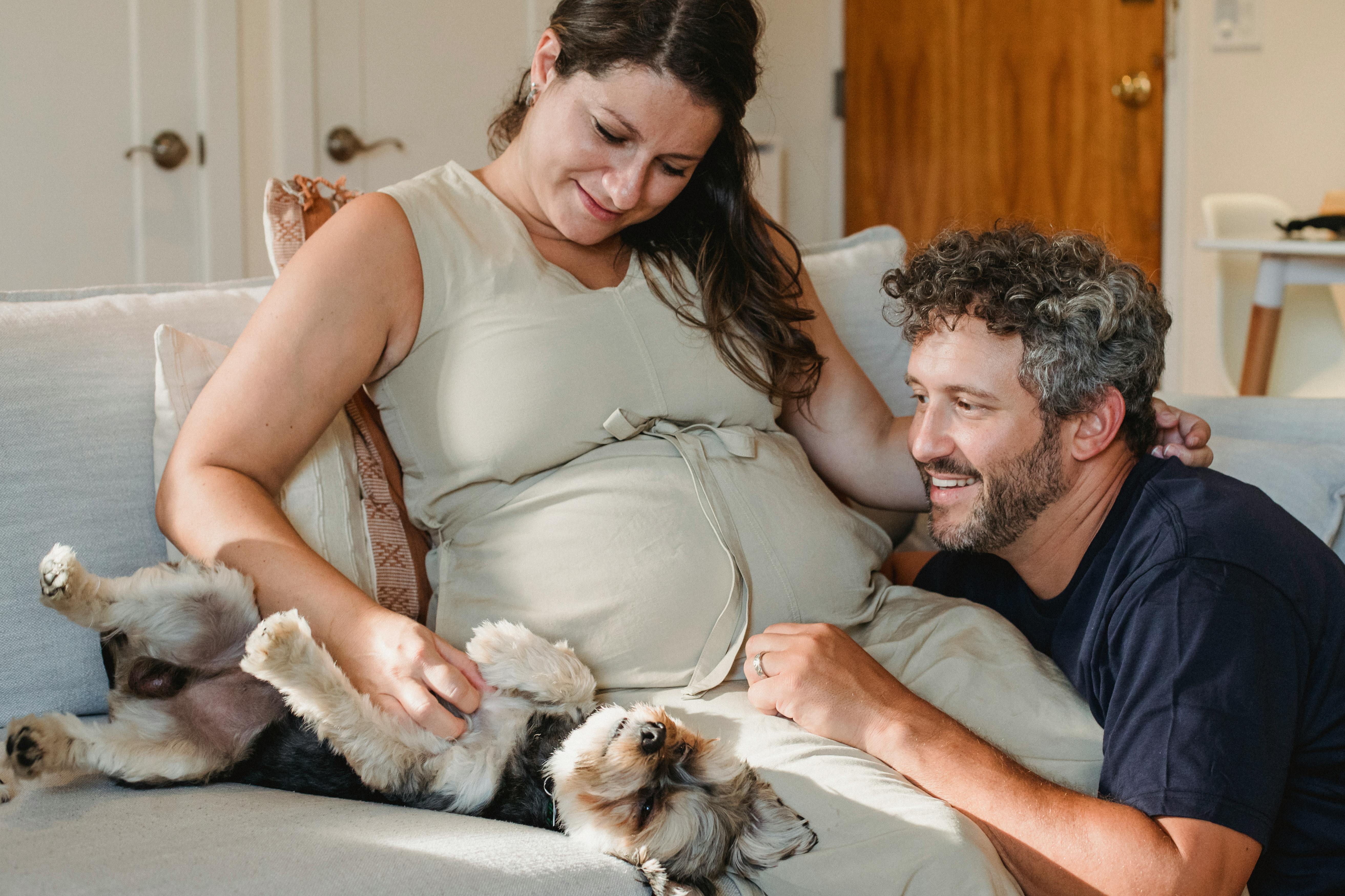 happy smiling couple expecting baby embracing small dog