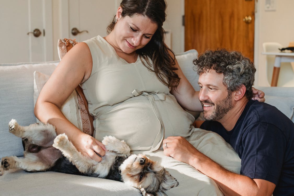 Happy smiling couple expecting baby embracing small dog