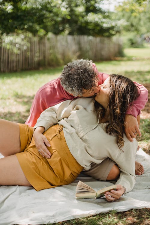 Romantic pregnant couple kissing during picnic in nature