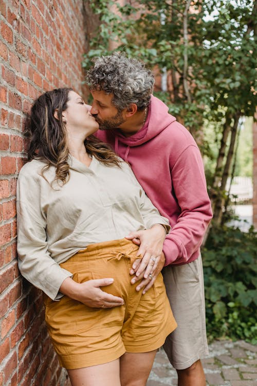 Romantic pregnant couple kissing in yard in daytime