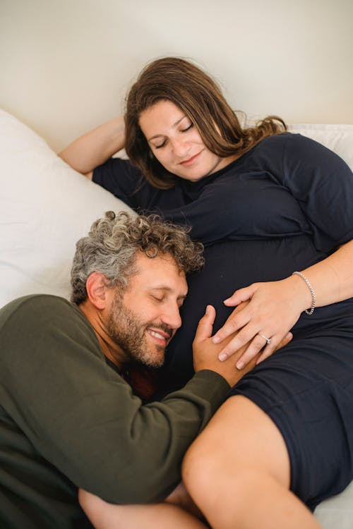 Loving pregnant couple cuddling and relaxing on bed during weekend at home