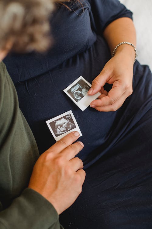 Unrecognizable pregnant couple with sonogram images in hands
