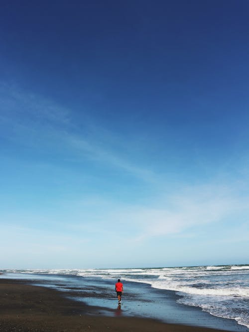 Free Man Walking on a Beach Alone in Distance  Stock Photo