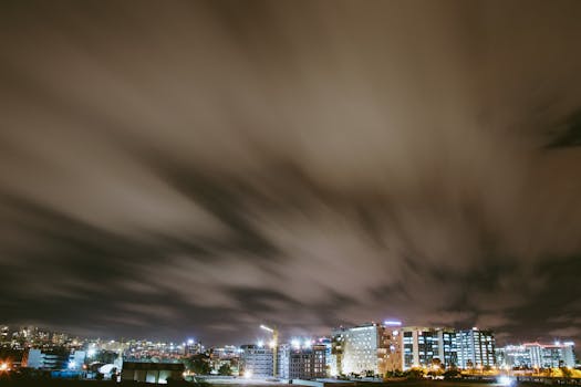 A cityscape at night featuring blurred clouds and illuminated buildings.