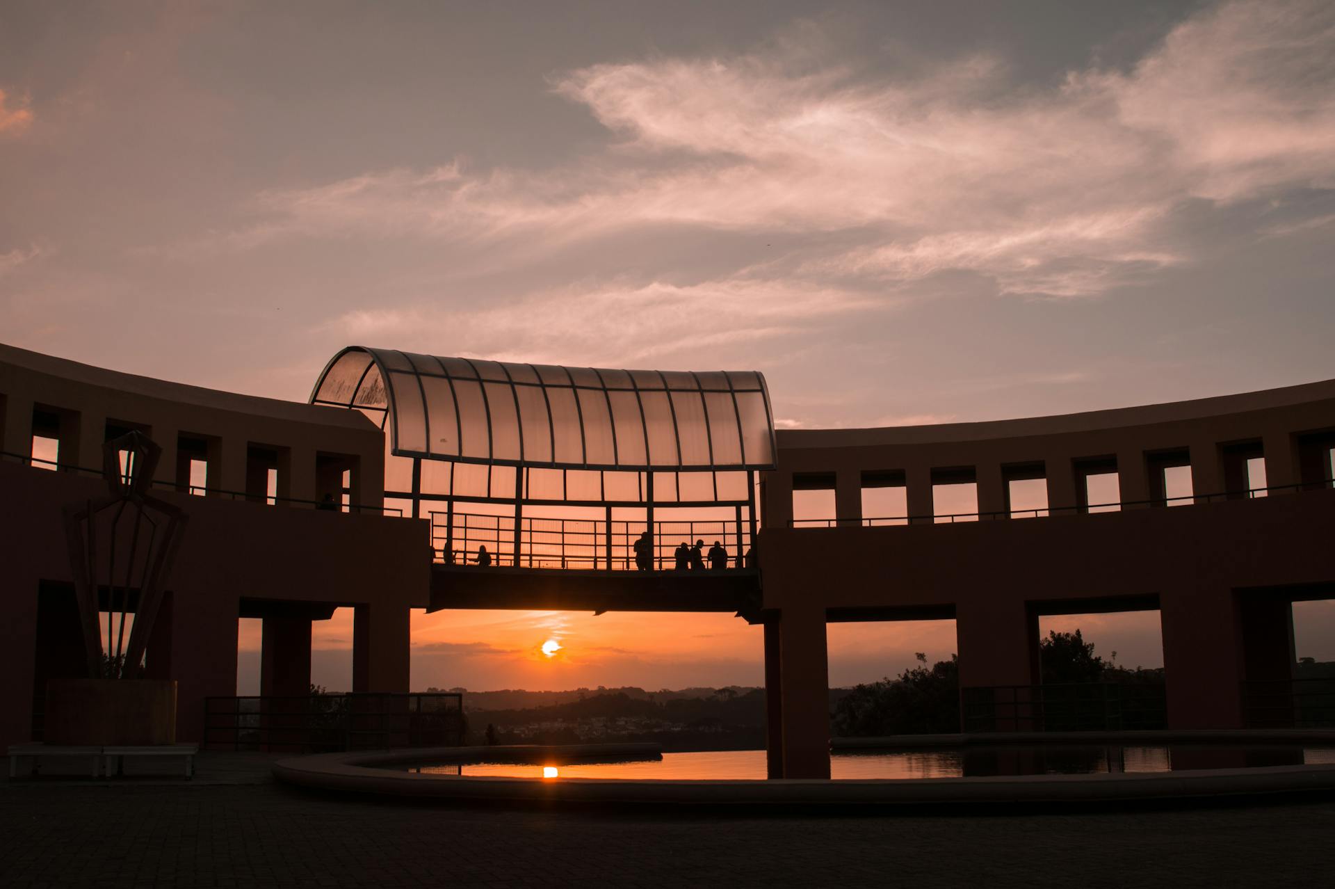 Stunning view of the Oscar Niemeyer Museum silhouetted against a vibrant sunset in Curitiba, Brazil.