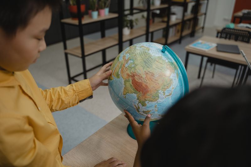 Kids explore a globe in a classroom, highlighting educational practices and curiosity.