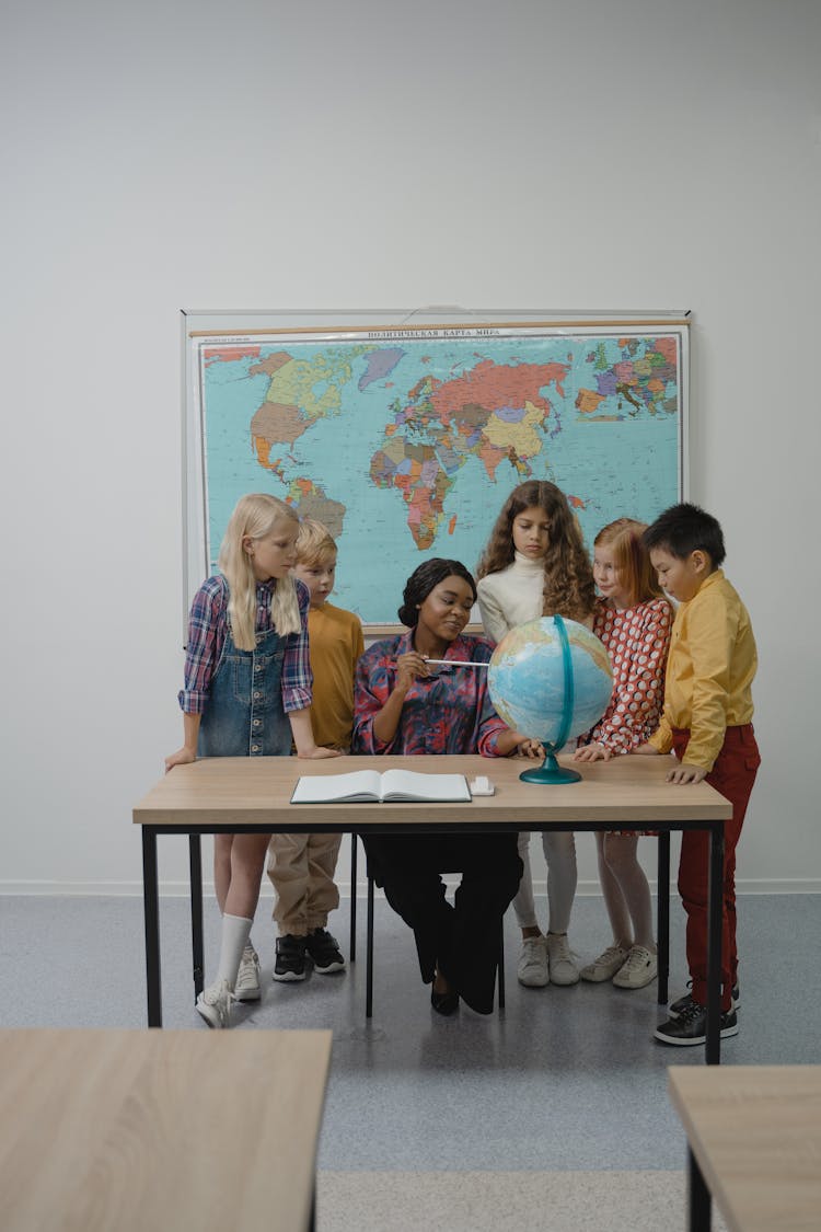 Teacher Teaching Students About Geography Using A Globe 