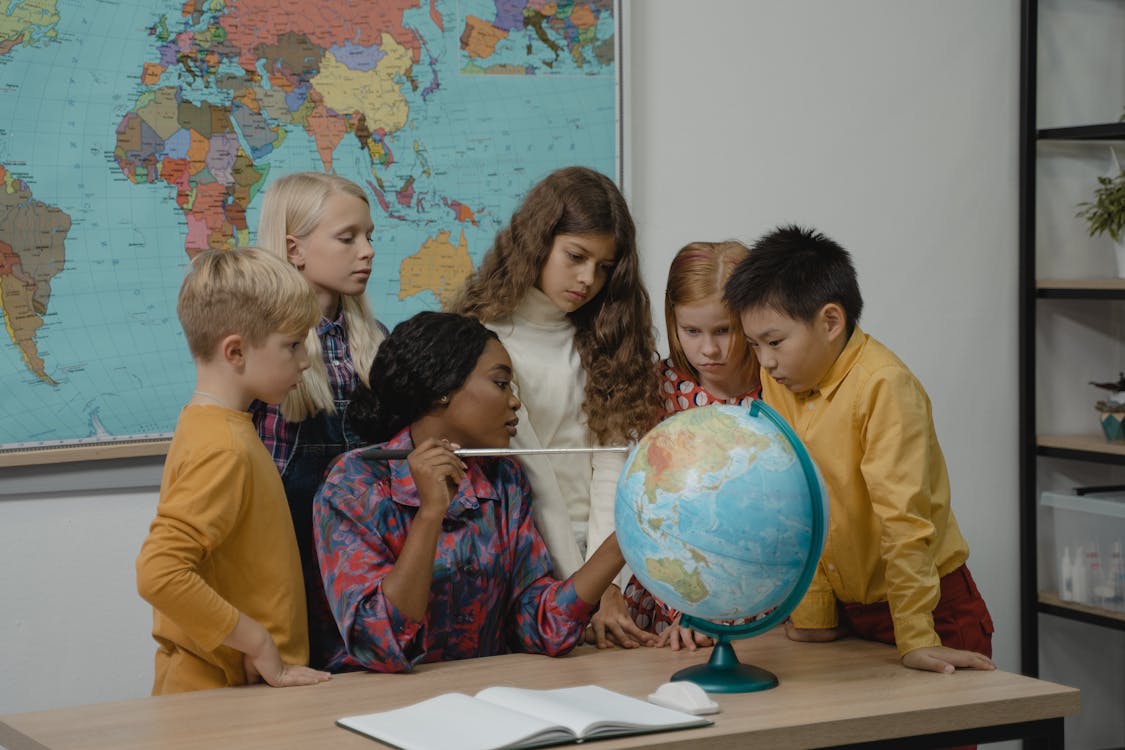 Free Teacher teaching students about Geography using a Globe Stock Photo