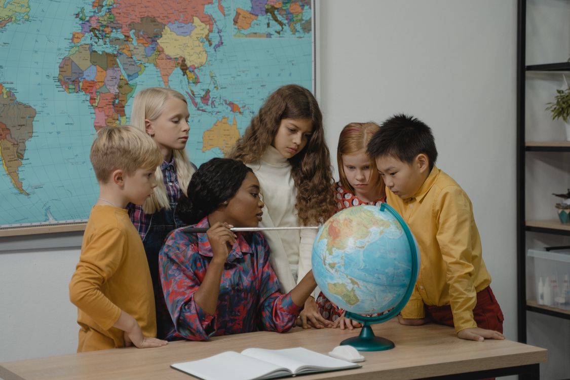 Teacher teaching students about Geography using a Globe · Free Stock Photo