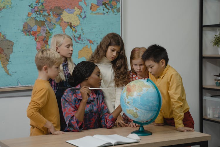 Teacher Teaching Students About Geography Using A Globe