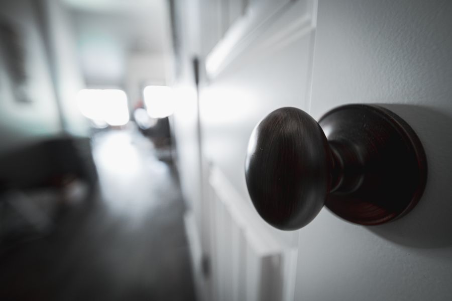 Professional handyman in uniform changing door lock hardware