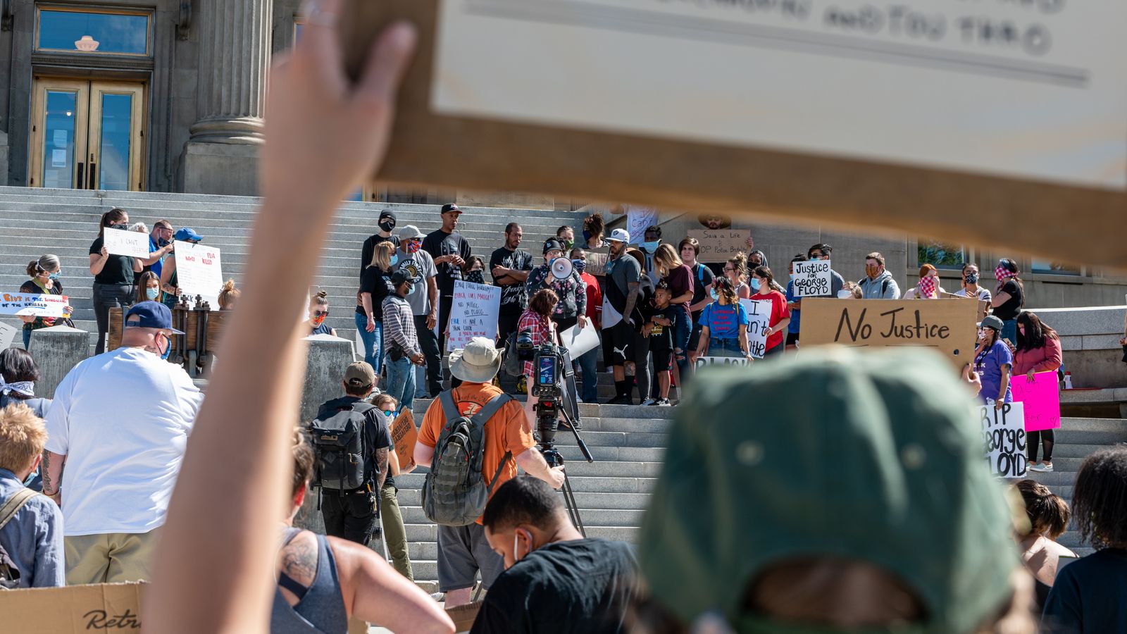 Protesters diverse people standing on stairs near building and holding placards with inscriptions about justice