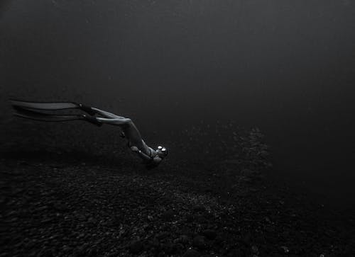 Monochrome Photo of a Person Underwater 