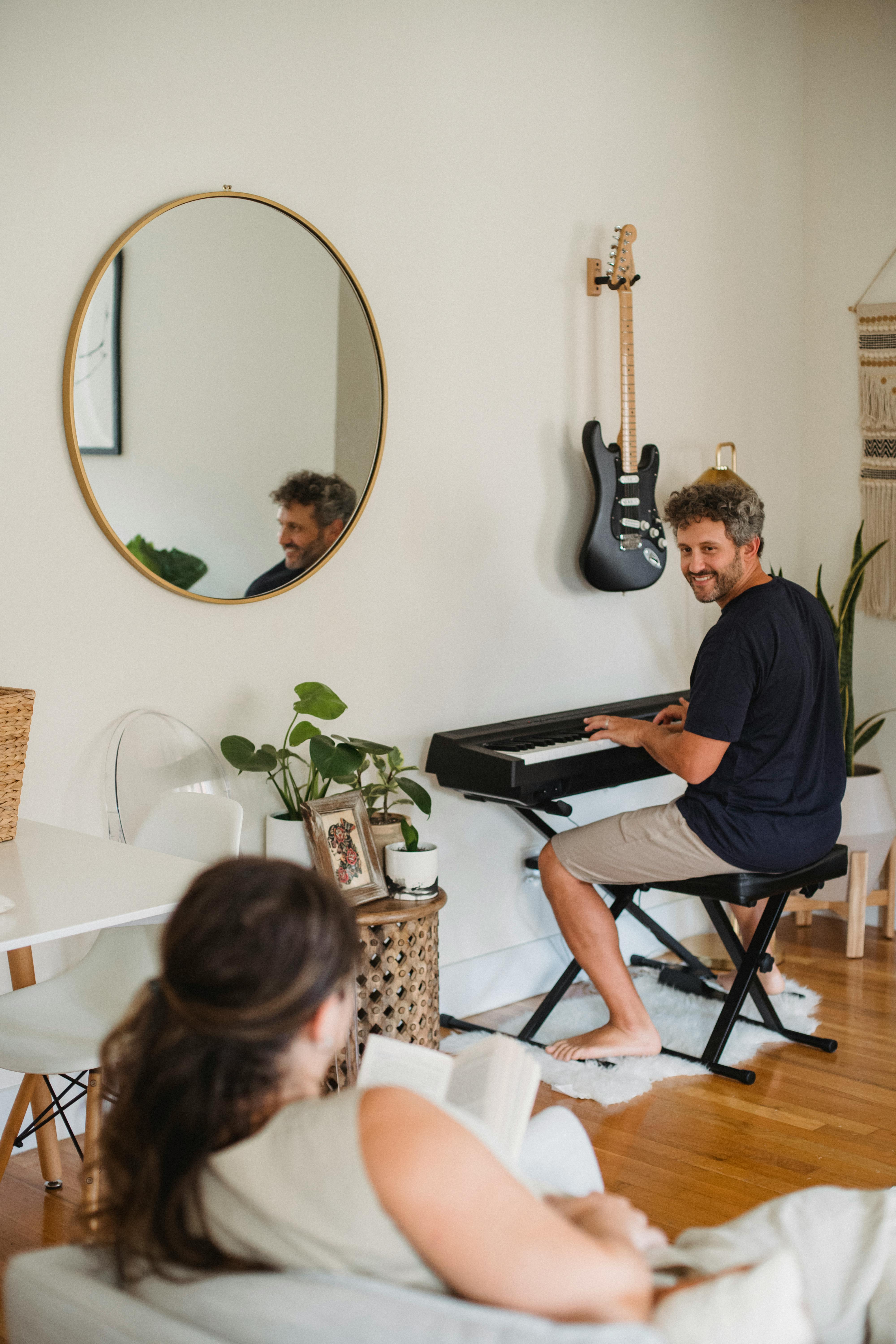 cheerful man playing synthesizer while resting at home with wife