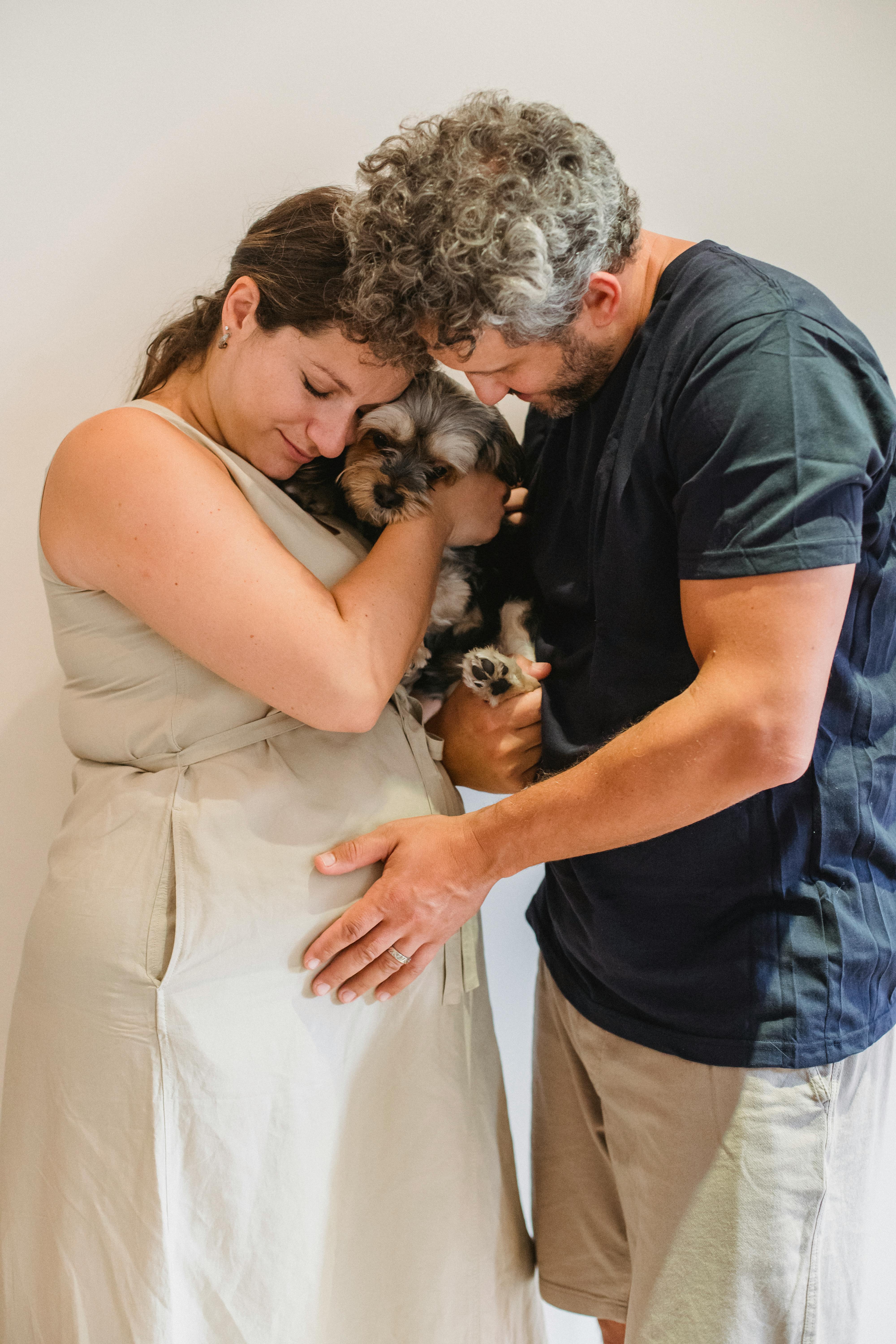 romantic pregnant couple stroking dog while resting at home