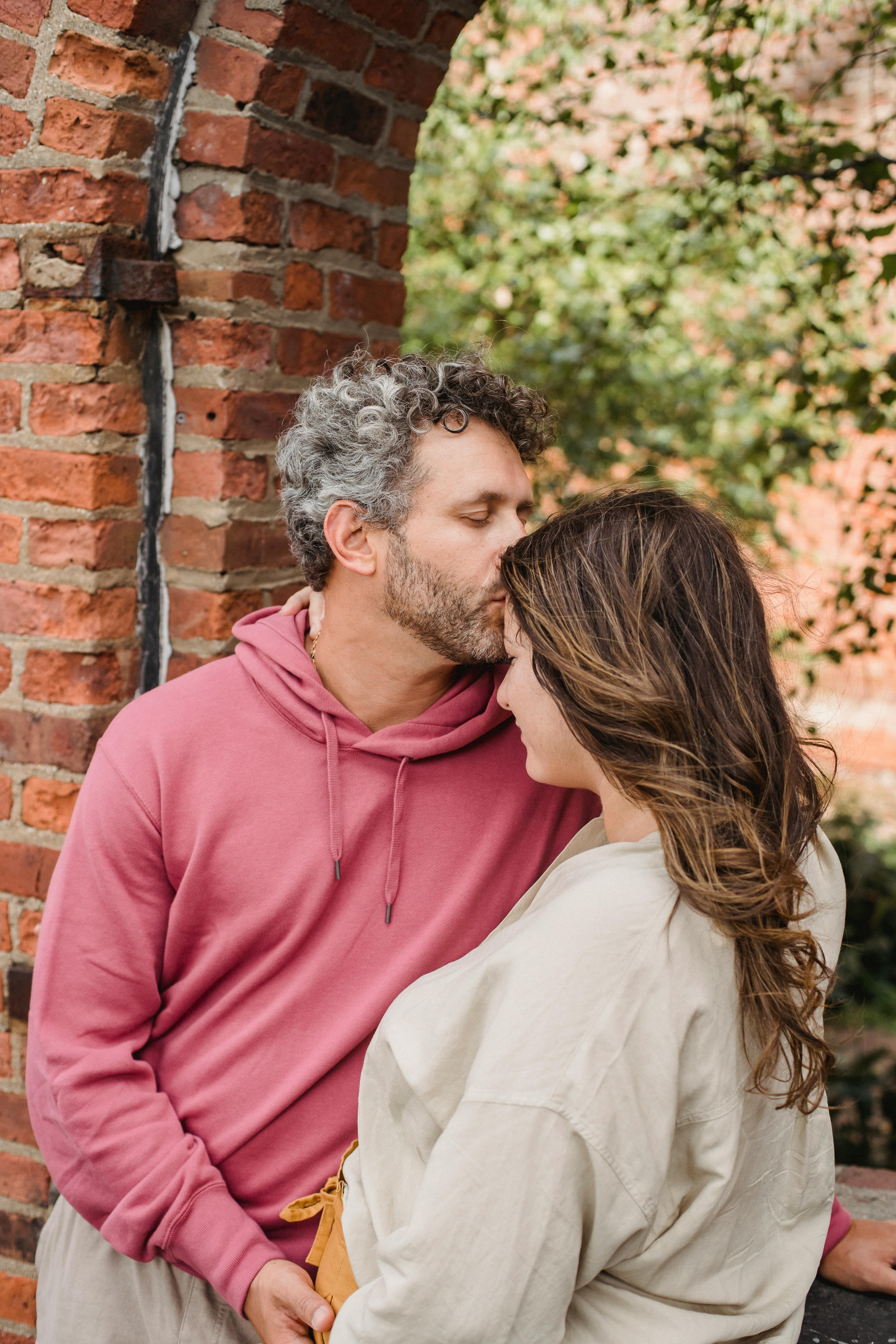 dreamy man with closed eyes kissing forehead of beloved pregnant wife