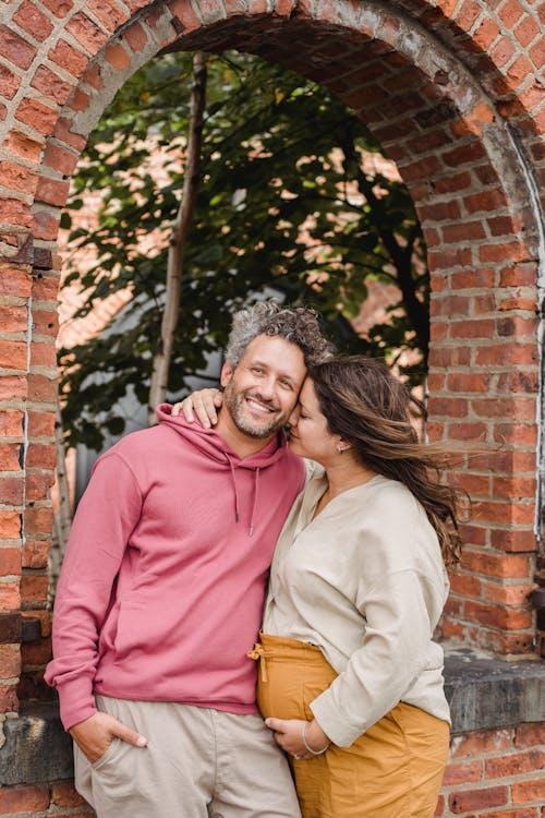 Pregnant woman embracing smiling husband with closed eyes