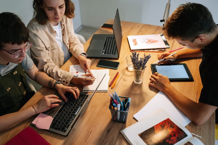 A shared desk covered in laptops and tablets, photo by Ivan S on Pexels
