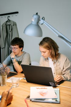 Two young professionals focus on a project together in a modern workspace.
