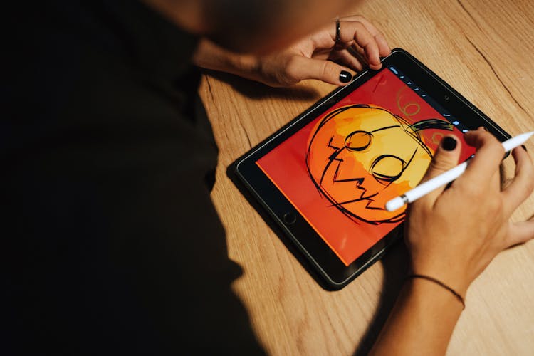 Person Drawing A Jack O'Lantern On A Tablet