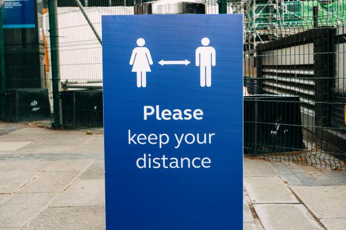 Free Banner with inscription Please Keep Your Distance and arrow between human figures on street during coronavirus epidemic Stock Photo