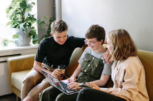 Free Three young professionals collaborate on a project in a modern indoor workspace, smiling and engaged. Stock Photo