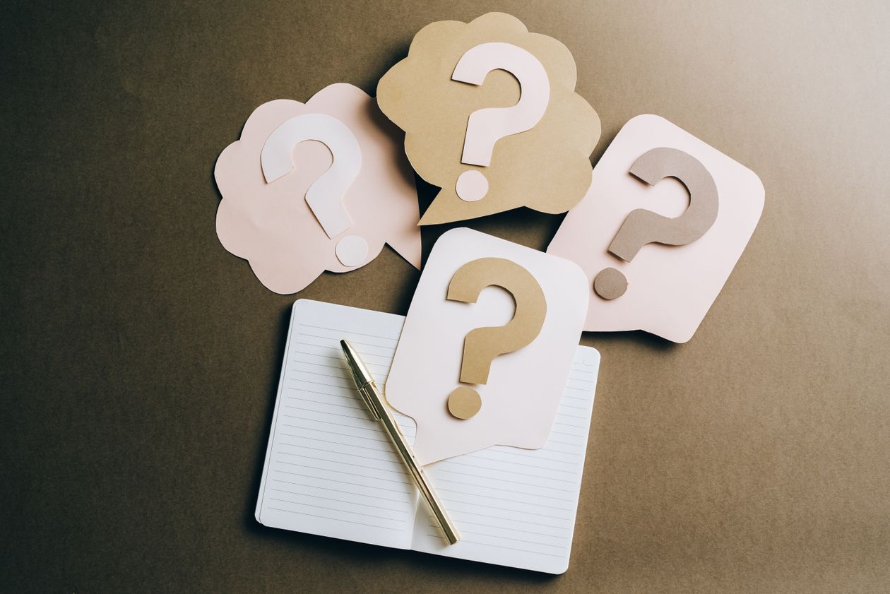 Flat lay of question mark paper crafts on a notebook, representing common questions about the Side Hustle Summit