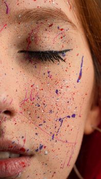 Vibrant artistic makeup close-up with colorful face paint and closed eyes, highlighting creative expression.
