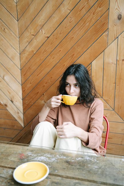 Young woman sipping a hot beverage indoors, evoking relaxation and warmth.