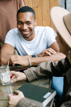 一名年轻人在咖啡桌旁随意交谈，脸上带着微笑