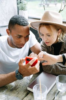 Two friends enjoying a moment together while looking at a smartphone indoors.