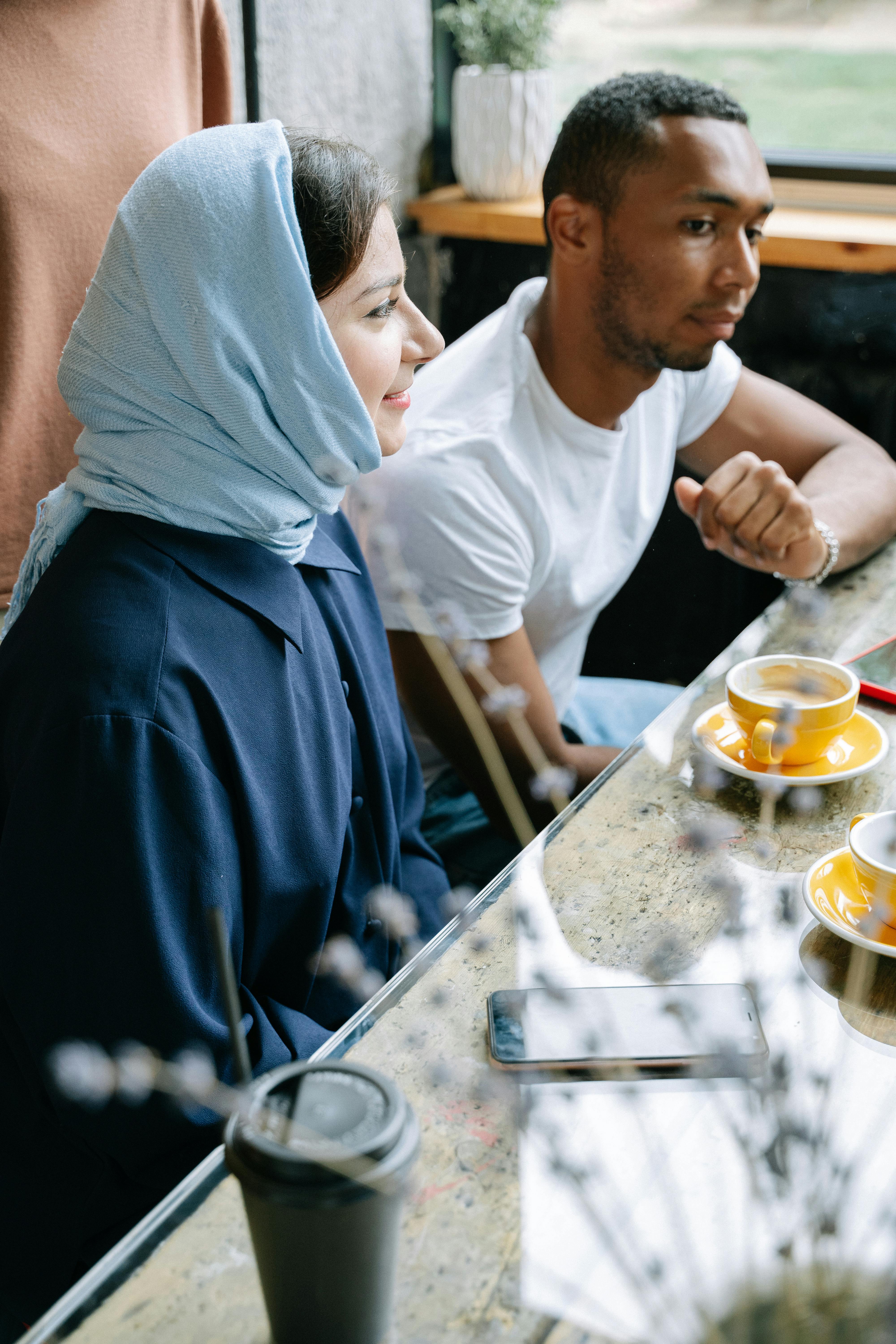A group of Bruneians sitting at a table in a coffee shop, enjoying Teh Tarik and engaging in conversation.
