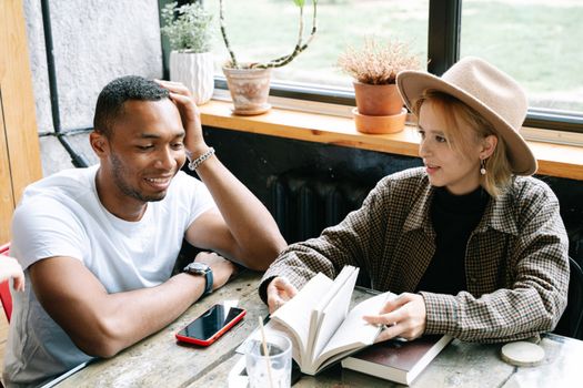Two people enjoy a casual conversation in a cozy café, surrounded by books and natural light.