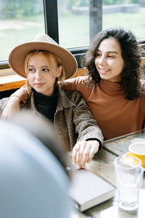 Free Two young women in casual attire enjoy a relaxed moment indoors, capturing friendship and warmth. Stock Photo