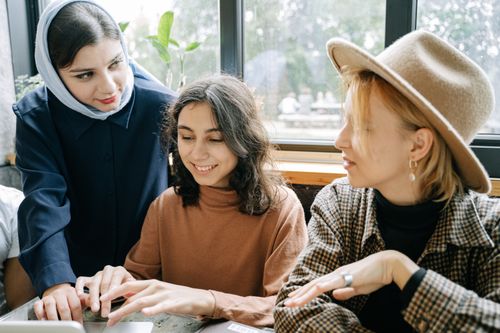 Free Three women collaborating in a bright, modern workspace, enhancing creativity and teamwork. Stock Photo