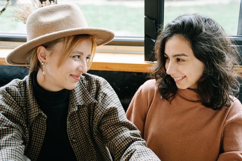 Free Two women sharing a joyful conversation indoors, fostering connection and smiles. Stock Photo