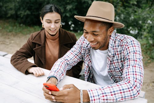 Woman And A Man Sitting On A Bench Using Smartphone