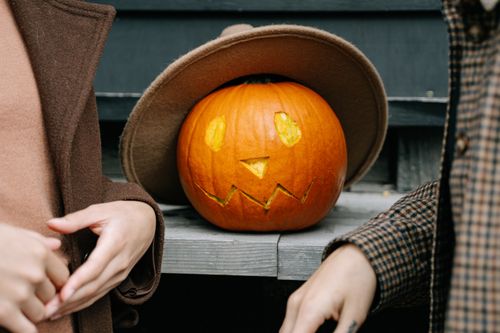 Free Pumpkin decorates autumn scene with carved face and cozy coats, perfect for Halloween feel. Stock Photo