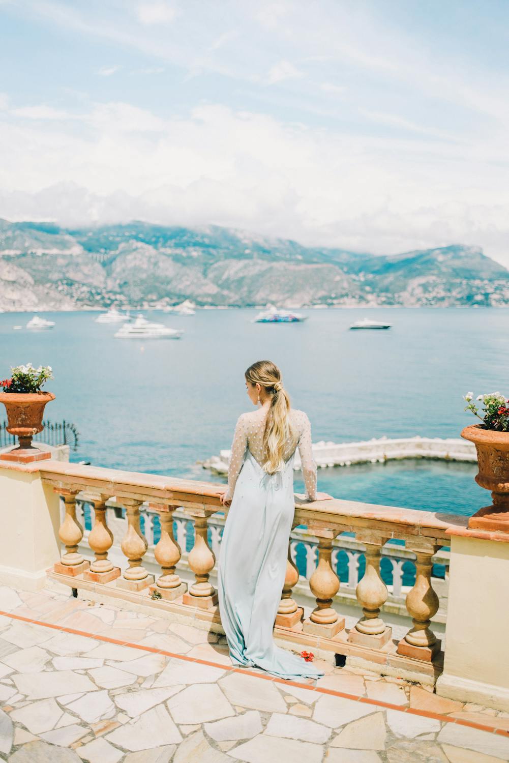 A woman posing on a balcony with a view of a lake