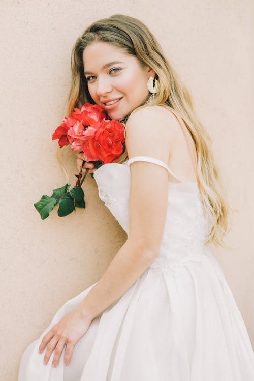 Femme En Robe Blanche Sans Manches Tenant Une Rose Rouge