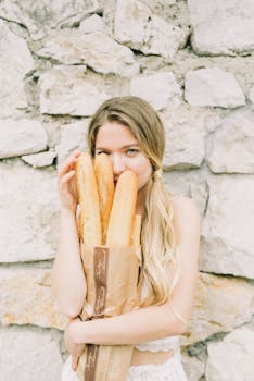 一位别致的白人女性手持长棍，在石墙前摆出姿势，展现时尚与生活方式