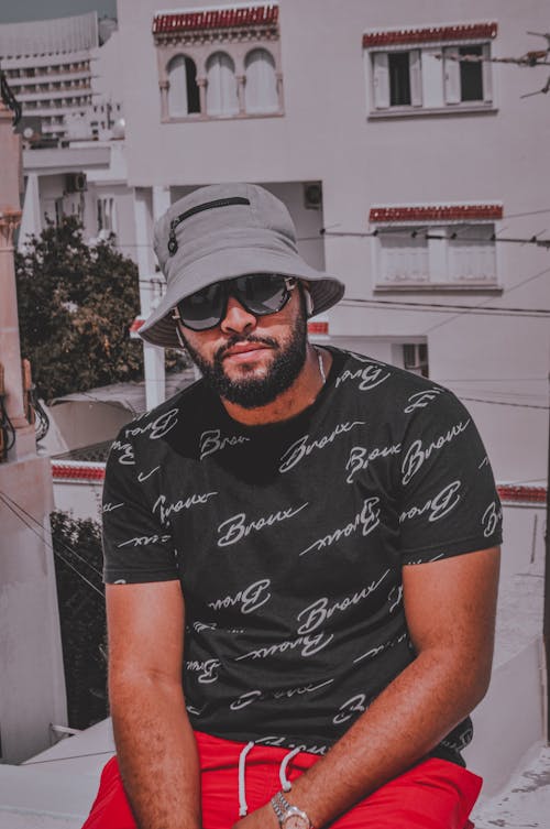 Bearded Man in Black T-shirt Sitting at a Balcony