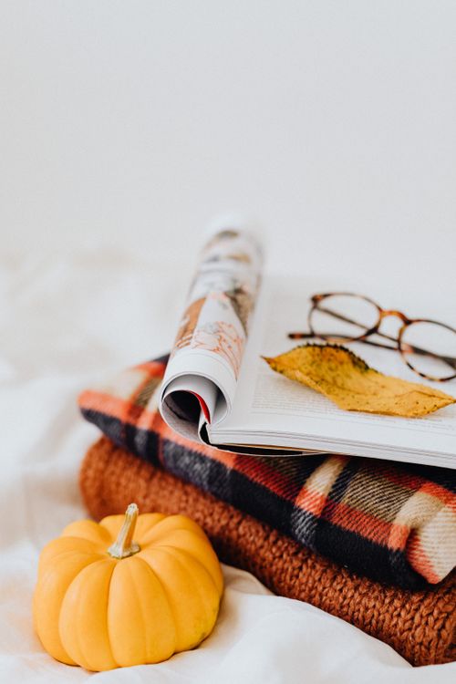 Free Warm autumn scene with an open book, glasses, and a small pumpkin. Stock Photo