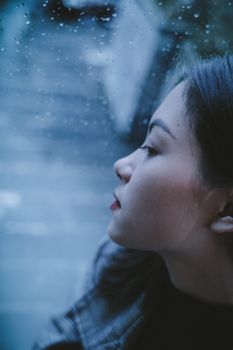 High angle of crop pensive teen girl enjoying being alone in rainy weather sitting by window