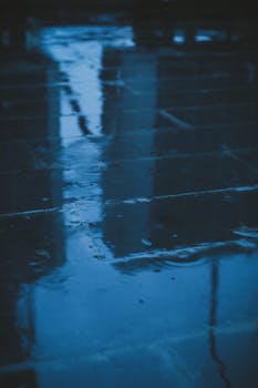 Smooth surface of wet concrete ground with water from rain with reflection of houses on street