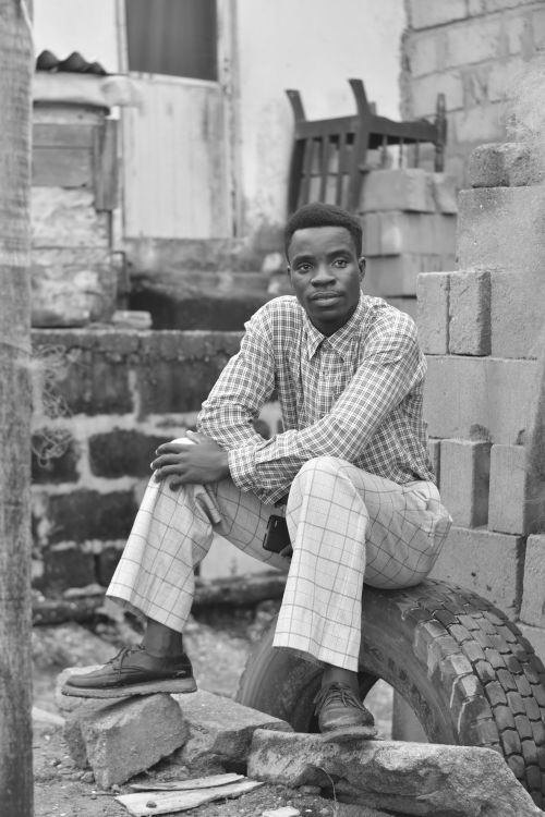 Free Black and white portrait of a stylish man sitting in an urban outdoor setting. Stock Photo