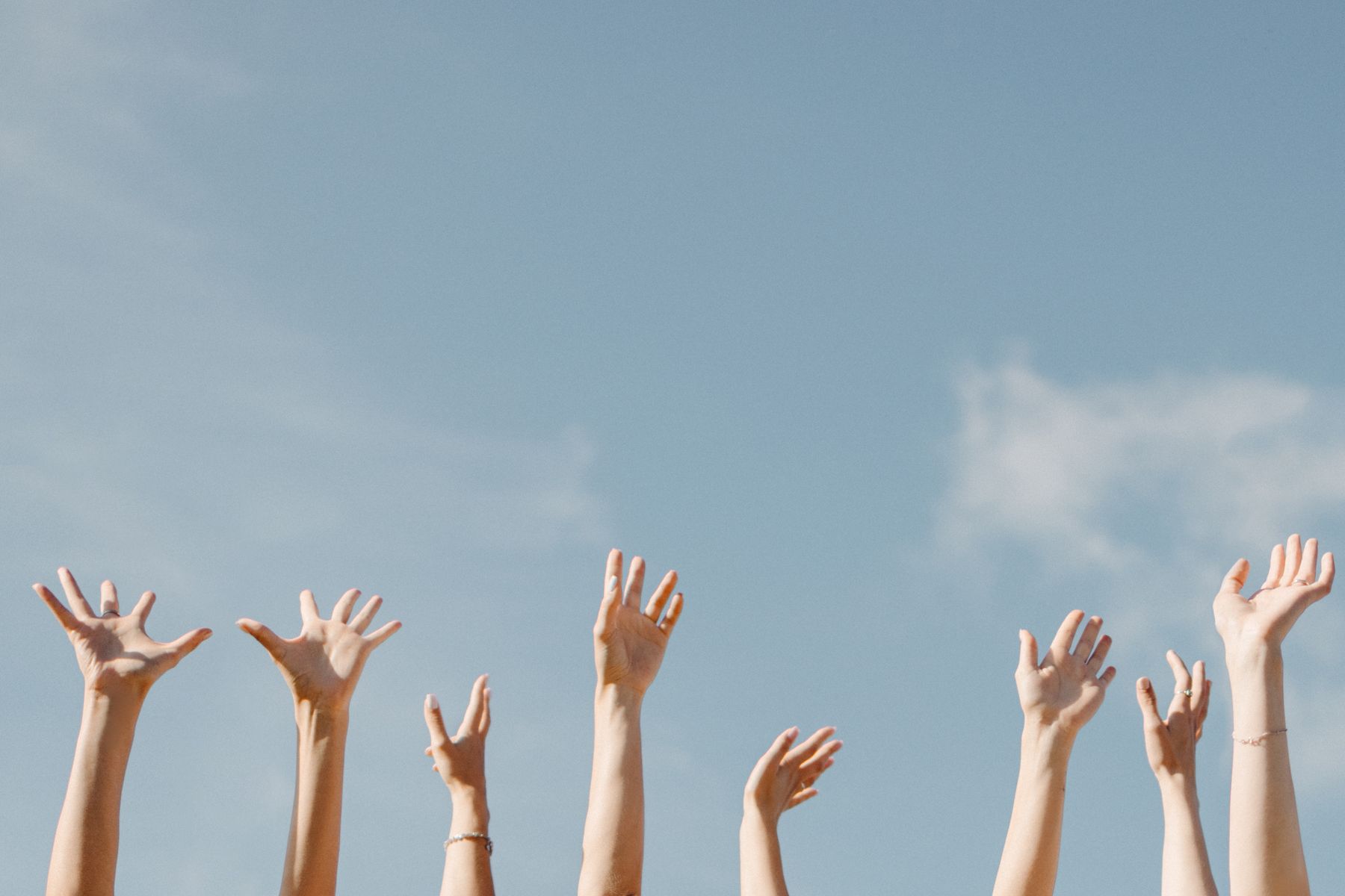 Raised hands against an open sky, photo by Maksim Goncharenok on Pexels