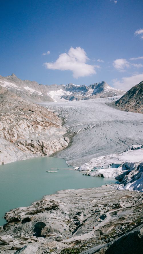 Free Scenic glacier landscape with pristine turquoise lake surrounded by rocky mountains under a clear blue sky. Stock Photo